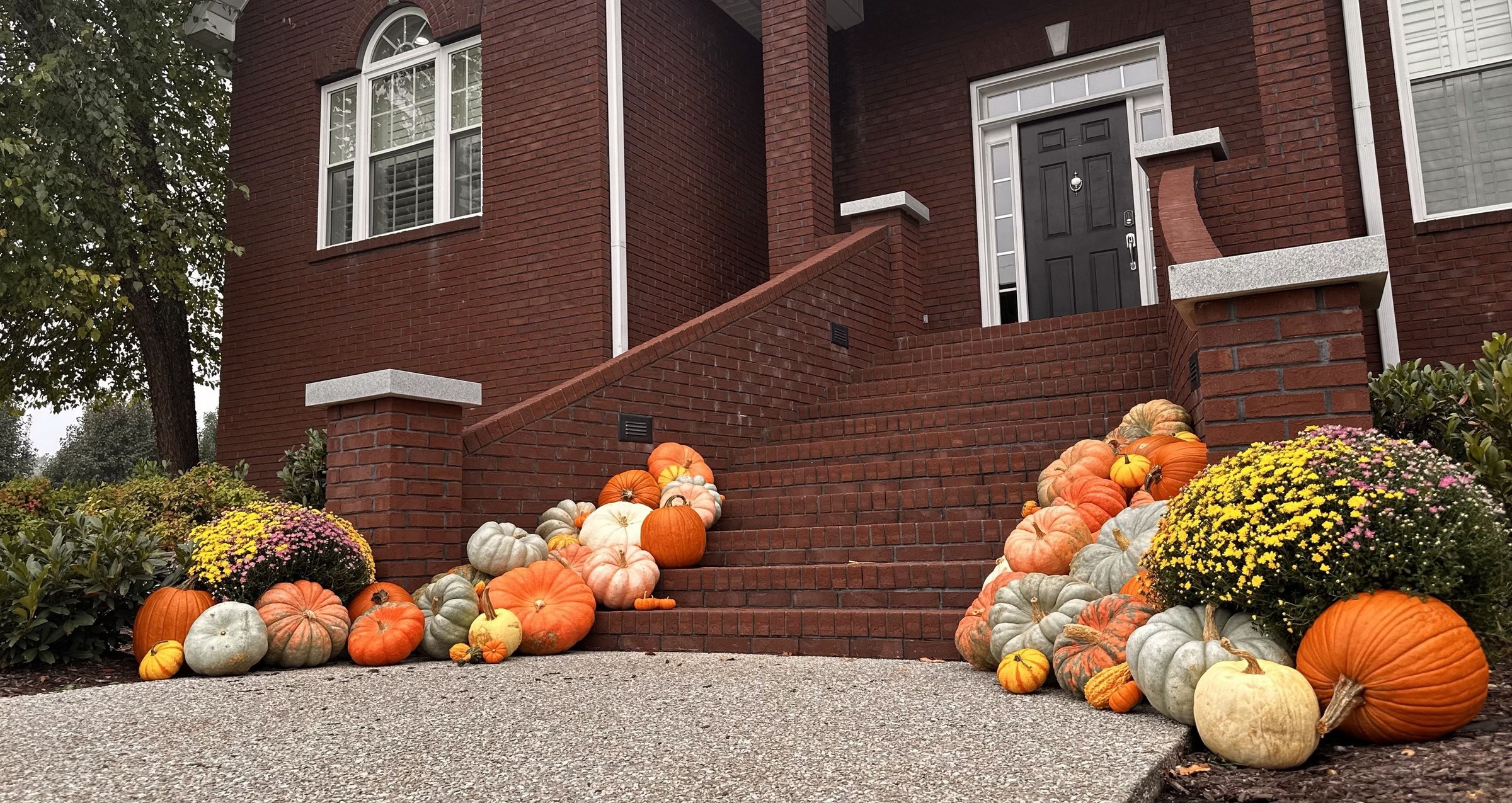 Red brick home with pumpkins lining both sides of the stairs