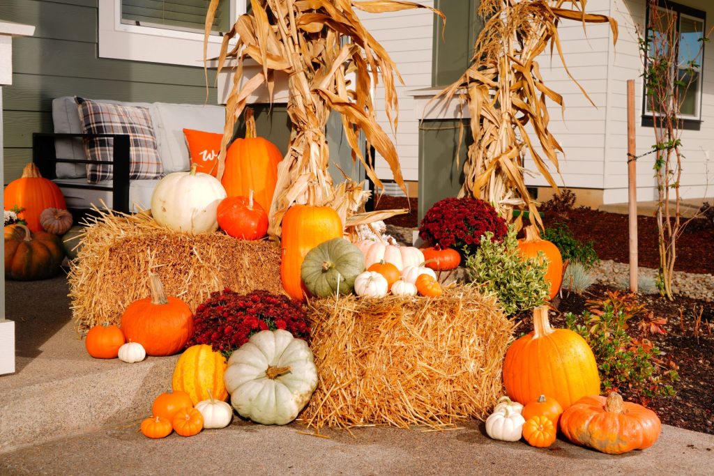 Hay bales, heirloom pumpkins, and corn stalks styled at a front entry