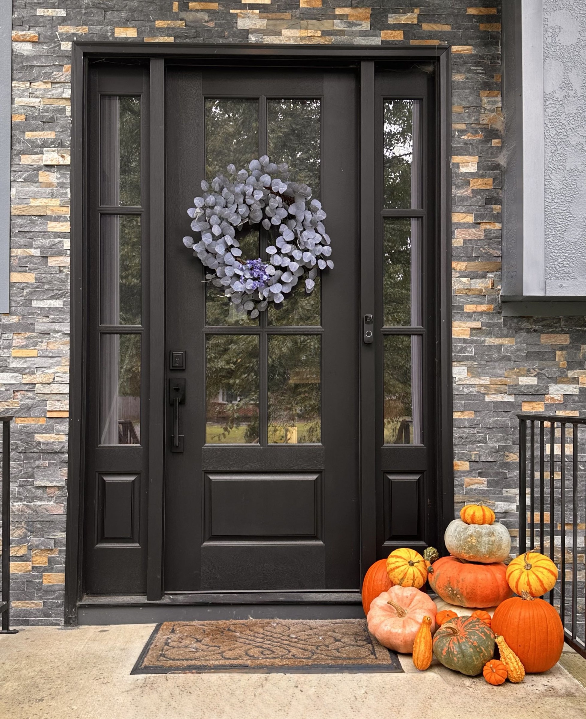 Black door stone entry with a small pumpkin grouping